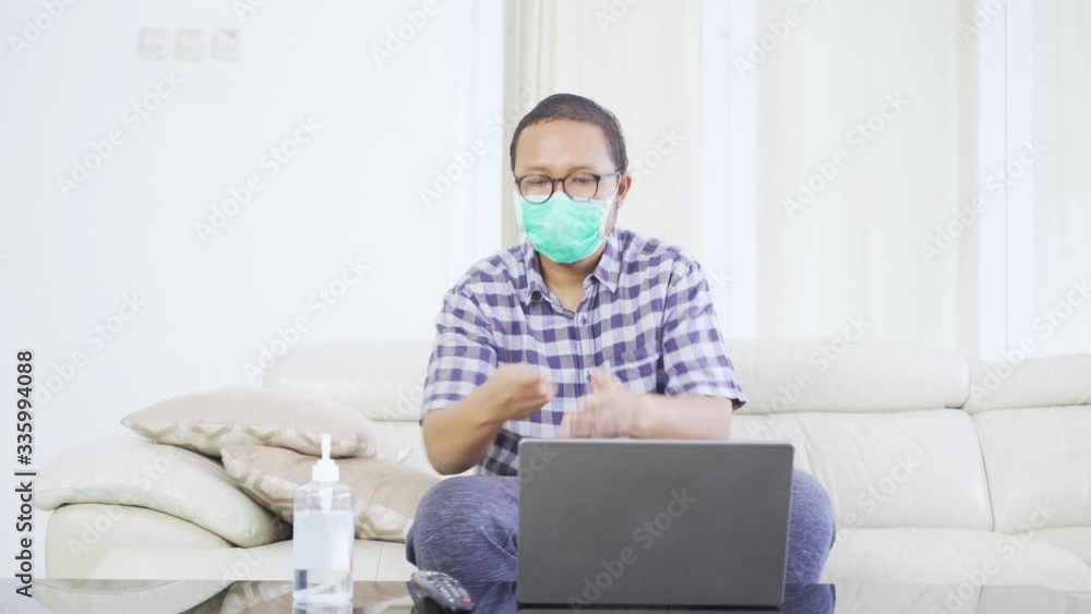 Young man using hand sanitizer before watching TV Young man using hand sanitizer before watching TV