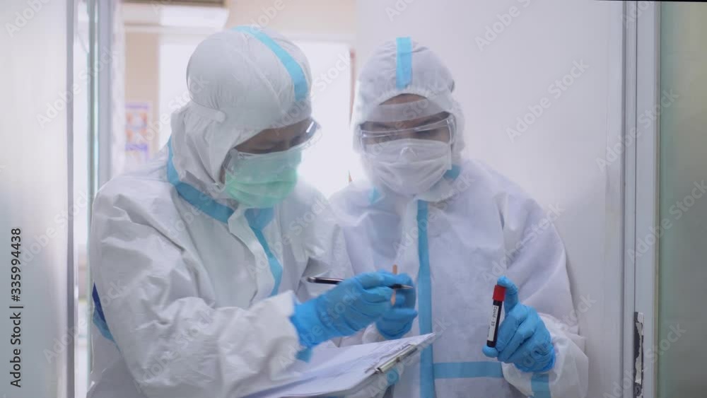 Two doctors in personal protective equipments including white suit, mask, face shield and gloves are discussing about treatment of pateint with coronavirus. covid-19, hospital, quarantine unit concept Two doctors in personal protective equipments including white suit, mask, face shield and gloves are discussing about treatment of pateint with coronavirus. covid-19, hospital, quarantine unit concept