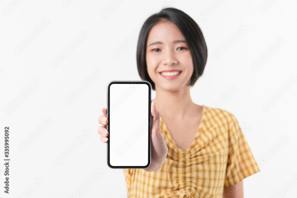 Cheerful beautiful Asian woman holding smartphone on white background. Take your screen to put on advertising.