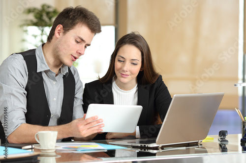 Employee helping coworker showing tablet photo