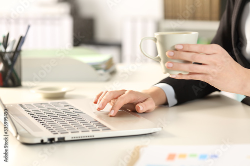 Executive hand using laptop holding a cup of coffee