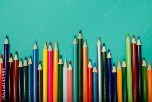 Colorful multicolor pencils arranged in a wave over blue background