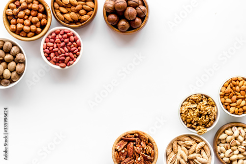 Nuts set in bowls on white background top-down frame copy space