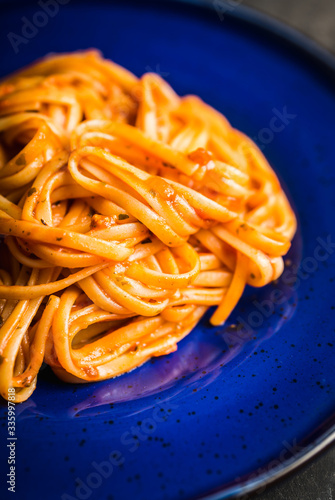 Traditional pasta with tomato sauce in blue plate on the rustic background. Selective focus.