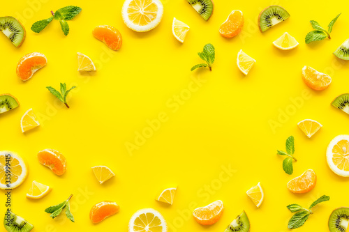 Slices fruites frame. Fruit salad concept with citruses  aplle and kiwi on yellow background top-down copy space