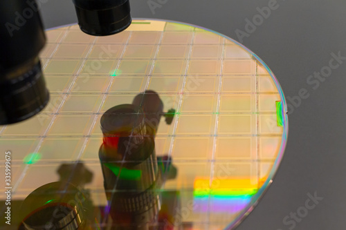 Close up of silicon wafer with microchips on machine process examining in microscope and checking quality . Selective focus. photo