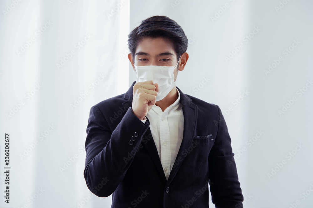 Young Asian businessman is cough and wearing a mask at workplace to prevent the  corona virus outbreak, white background