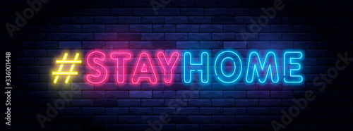 I Stay home hashtag in neon style. Coronavirus pandemic protection and prevention effort. Social activity message. Self-isolation and quarantine. To stay at home brightly illuminated neon sign on wall photo
