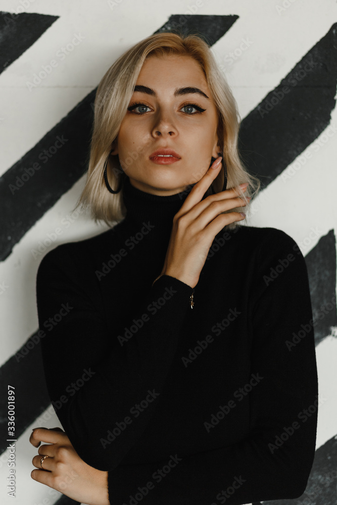 Young blonde girl on the background of the black and white wall Young blonde girl on the background of the black and white wall