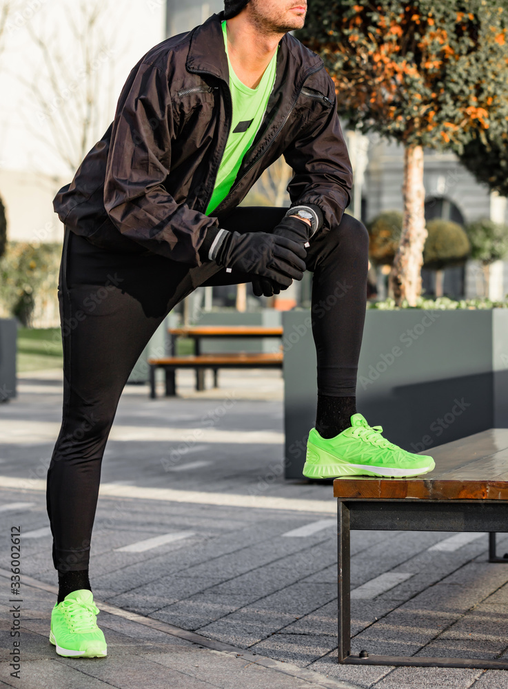 Man tying running shoes in urban park. Man tying running shoes in urban park.