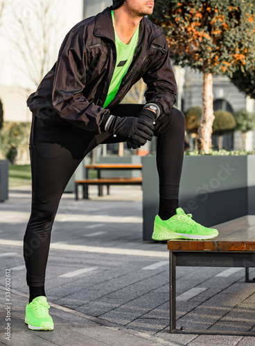 Man tying running shoes in urban park.