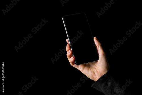 Person holding in hand mobile phone, isolated on black background