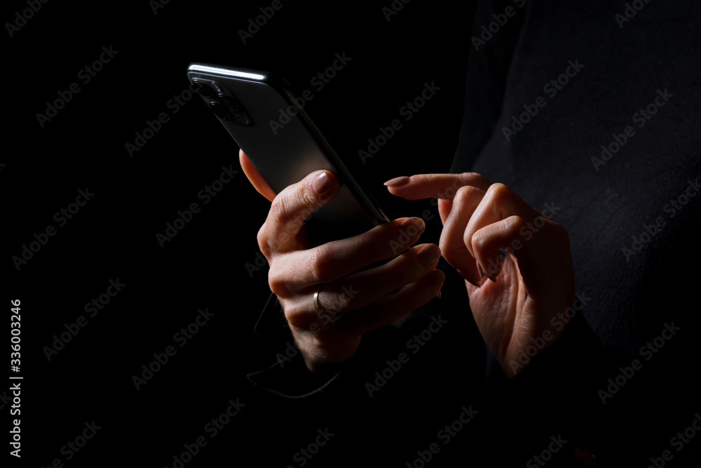 Person holding in hands and typing on mobile phone, photo isolated on black background Person holding in hands and typing on mobile phone, photo isolated on black background