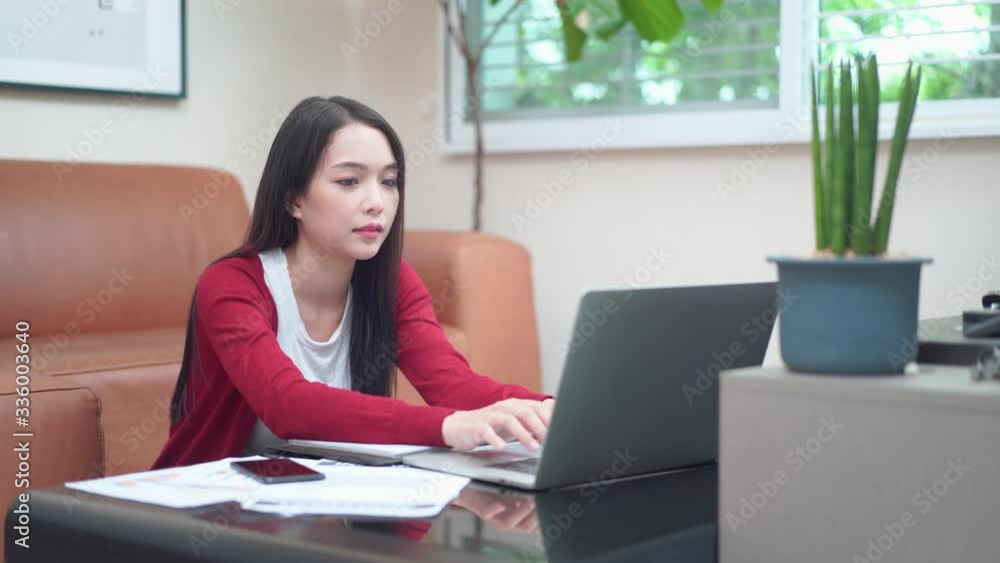 Young Asian freelance using computer laptop and receive cell phone while work from home Young Asian freelance using computer laptop and receive cell phone while work from home