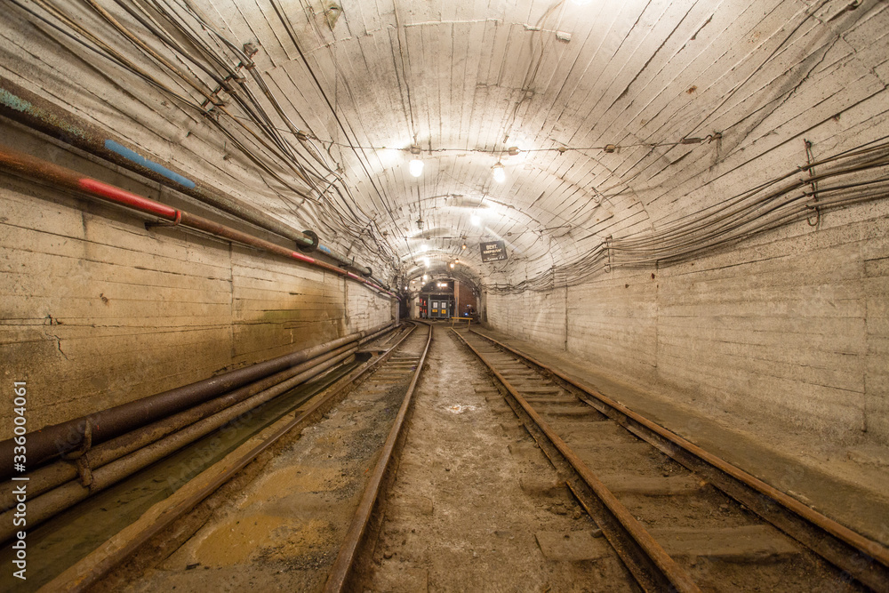 Underground gold mine tunnel with rails two ways and light Underground gold mine tunnel with rails two ways and light