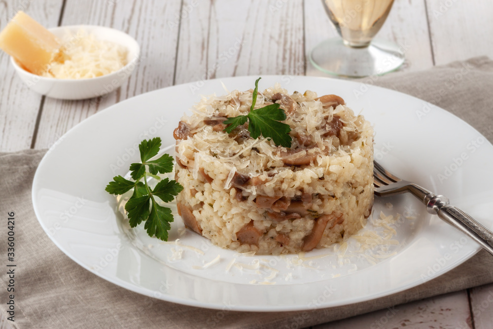 Wild mushroom risotto with parsley and parmesan on a white wooden background Wild mushroom risotto with parsley and parmesan on a white wooden background