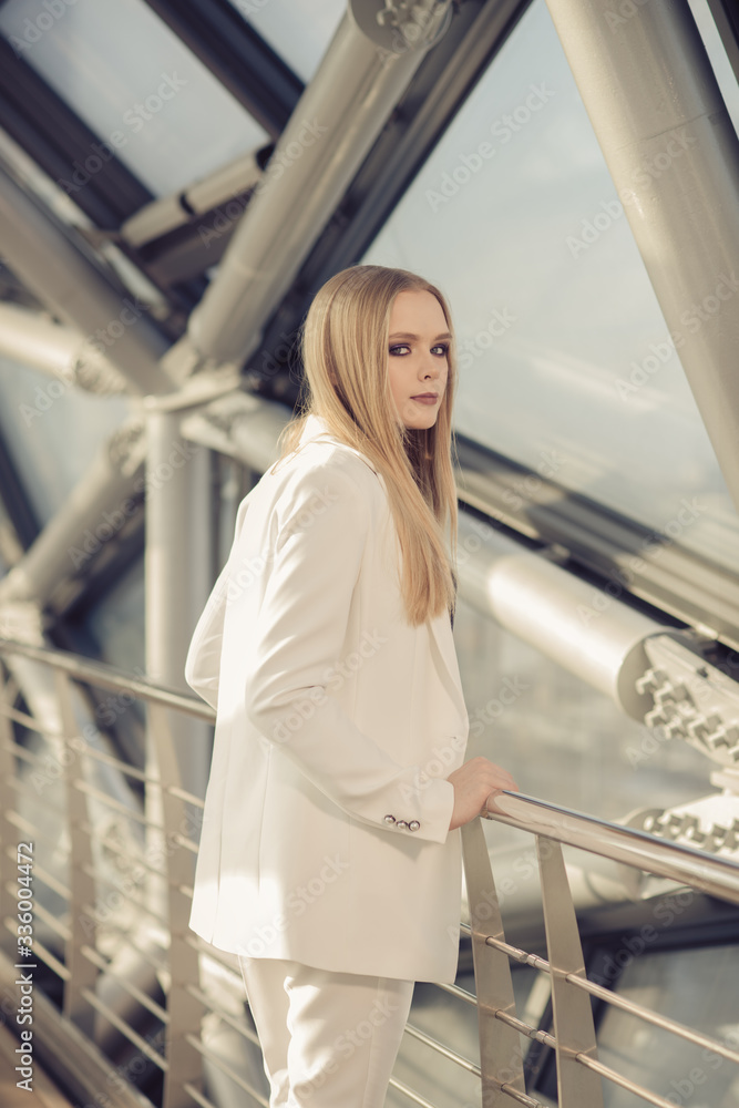 A young businesswoman in casual clothes, standing in a bright corridor and thinking, making an important decision. A young businesswoman in casual clothes, standing in a bright corridor and thinking, making an important decision.