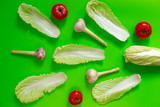 Flat lay vegetable background geometric lie fresh leaves of Chinese cabbage, red tomatoes and fresh garlic on a green