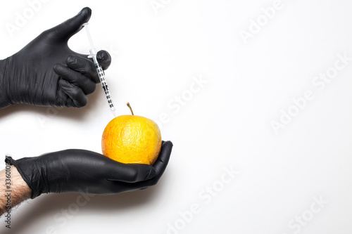 Male hands in medical gloves with wrinkled apples and a syringe in hands on a white isolated background. Botox injections and skin care.