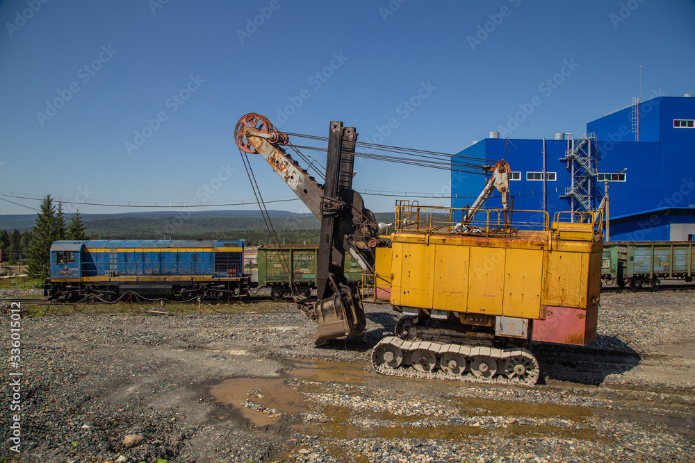 Freight train on railway railroad and excavator power shovel on the mining site 