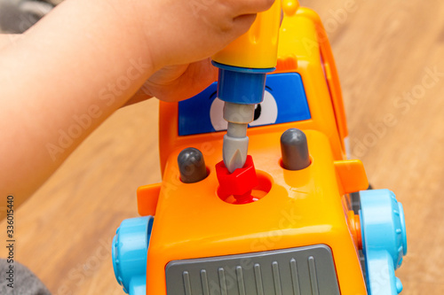 Small kid playing with toy constructor tractor close up