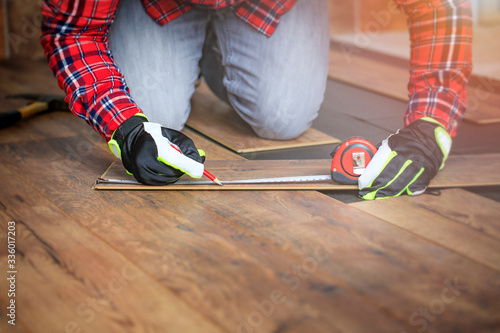 Work when installing a laminate floor. Professional floor work measuring in the room. photo