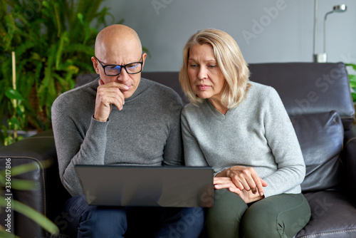 Fotografía Elderly mother sit rest on sofa with grown-up son watch video on modern laptop,middle-aged mom rest in living room with adult child use computer family weekend together