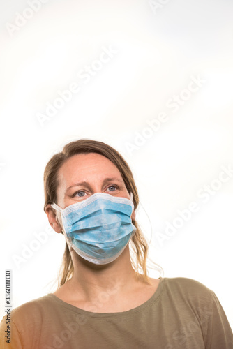Coronavirus, blonde girl with protective mask against coronavirus. Pandemic COVID-19 concept. Light background with copy space.