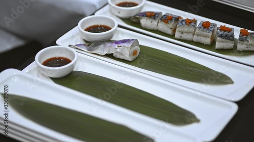 chef in asian restaurant serving sushi on leaf lrrl. caviar decoration. putting meal on plate with soy sause. oncept catering business and cooking. healthy japanese food photo