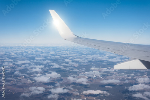 Wing of an airplane flying above the clouds, air transport to travel. back light sun beam.