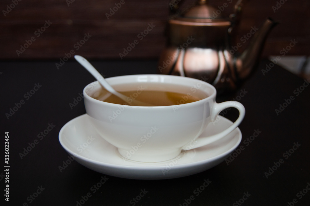 White tea cup with saucer and tea spoon on dark background. White tea cup with saucer and tea spoon on dark background.