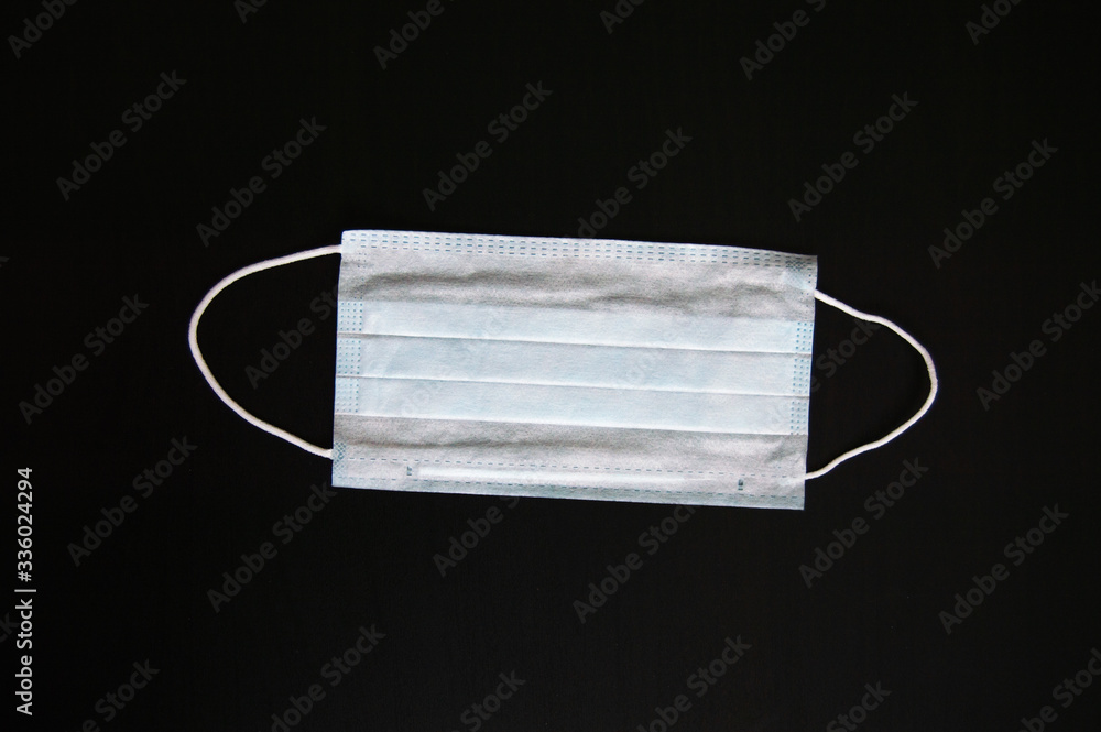 Antiviral medical mask for protection against coronavirus. Surgical protective mask. Medical respiratory bandage face on black background. Prevention of the spread of virus and pandemic COVID-19. Antiviral medical mask for protection against coronavirus. Surgical protective mask. Medical respiratory bandage face on black background. Prevention of the spread of virus and pandemic COVID-19.