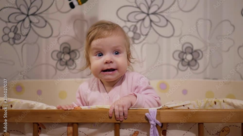 Little baby rocking in bed. Not an obedient little girl. A cute baby stands in her crib.