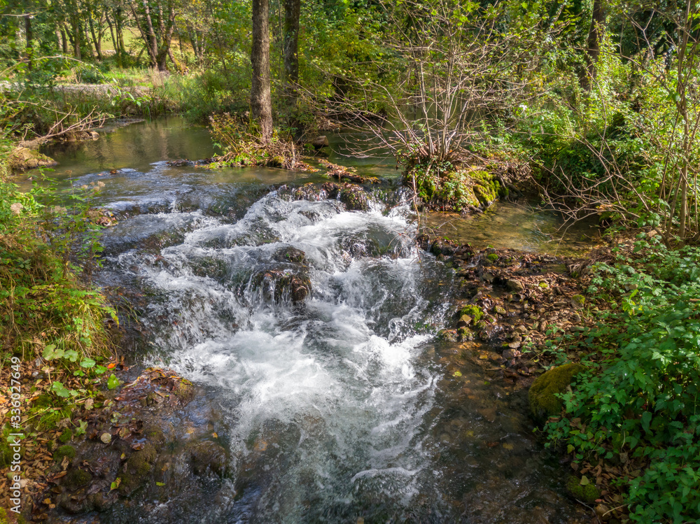 Fototapeta premium Cascades on the Janj mountain stream in the forest, painted with autumn colors near Sipovo. - Image