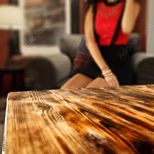 Desk of free space for your decoration and blurred home interior with woman legs 