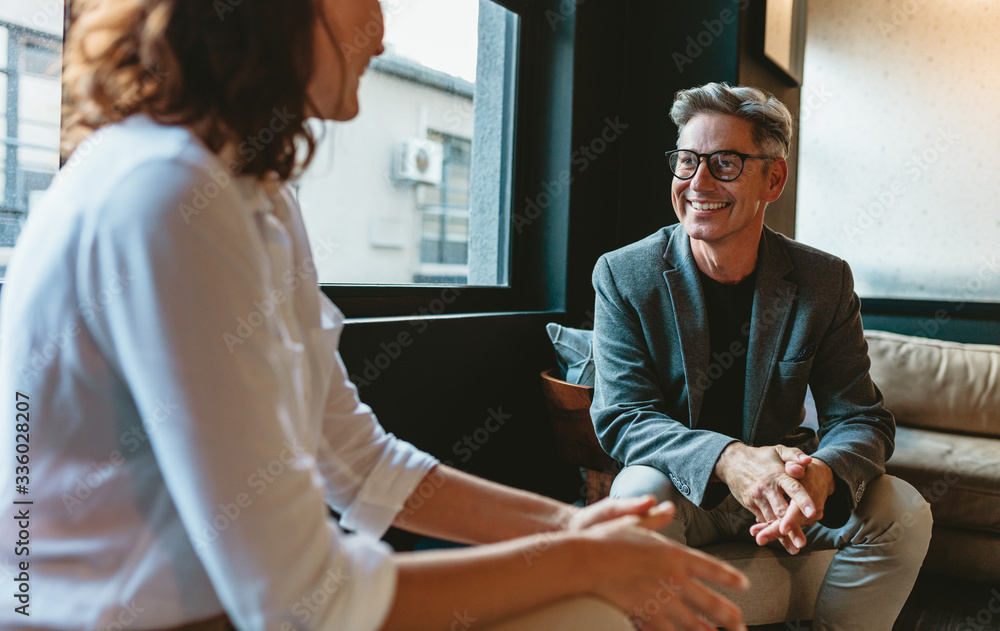 © Jacob Lund - Businessman talking with female colleague in office lobby