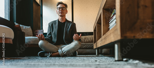 Mature businessman doing yoga meditation in office lounge