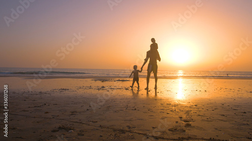 Father with kids playing in the beach at sunset