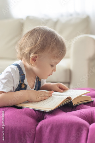 Little girl learning to read at home. My daughter looks at the book.