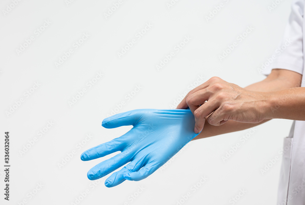 Woman doctor putting blue latex medical gloves on white background.Surgeon wearing gloves before surgery at operating room.Risk and infection control concept.