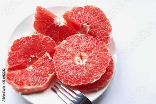 sliced ​​red grapefruit on a white plate on a white background