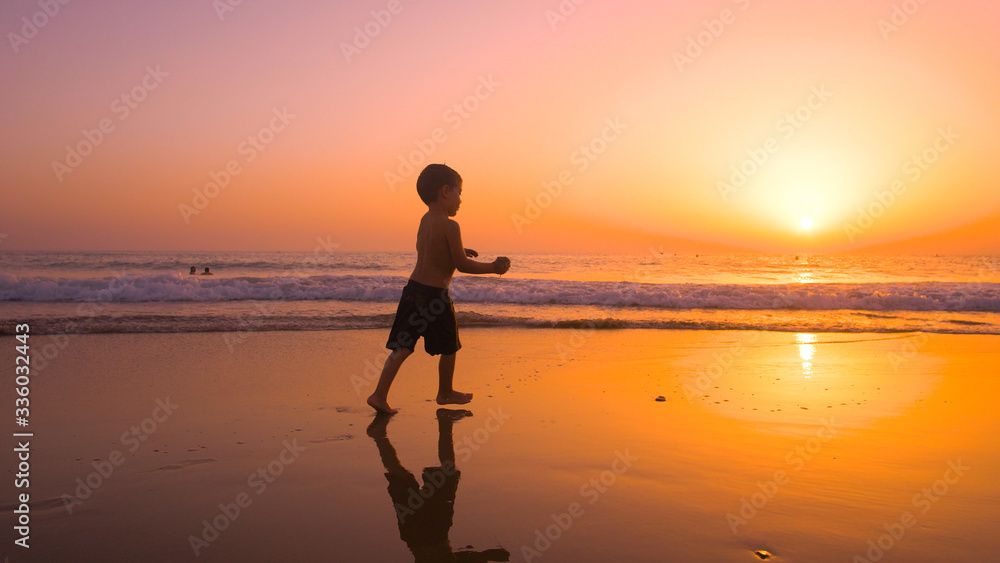 A little boy enjoying and playing in the beach at sunset