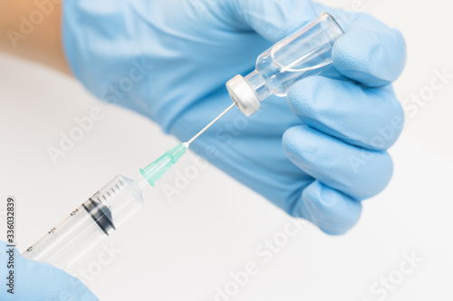 Doctor's hand holding medicine bottle and syringe isolated on white background.Nurse using syringe are vaccination to patient for influenza protection.Coronavirus vaccine against concept.