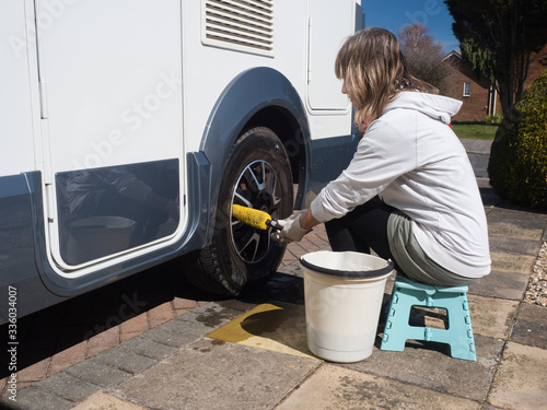 Fotografija A lady motorhome owner cleans the wheels with a yellow wheel brush