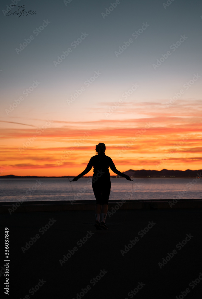 silhouette of a woman running on the beach at sunset