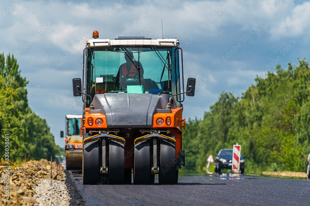 Road roller flattening new asphalt. Heavy vibration roller at work paving asphalt, road repairing. Selective focus. Road roller flattening new asphalt. Heavy vibration roller at work paving asphalt, road repairing. Selective focus.