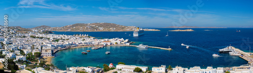 Panorama of Mykonos town Greek tourist holiday vacation destination with famous windmills, and port with boats and yachts and cruise liner. Mykonos, Cyclades islands, Greece