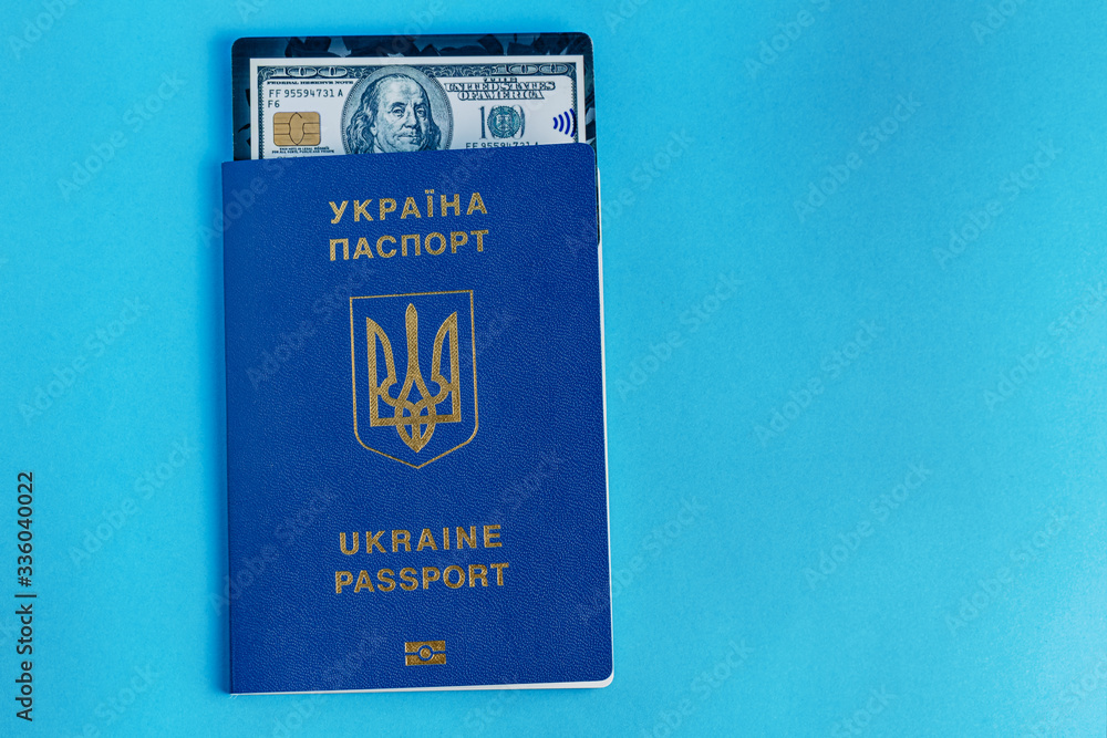 Naklejka premium Ukraine passport with black dollar bank card on a blue background