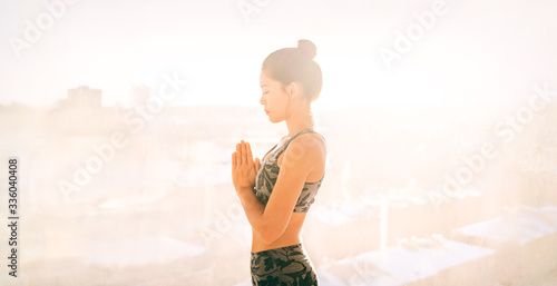 Yoga at home meditation exercise for mental health wellness well-being during self isolation quarantine of COVID-19 Coronavirus outbreak pandemic. Asian fit girl meditating .