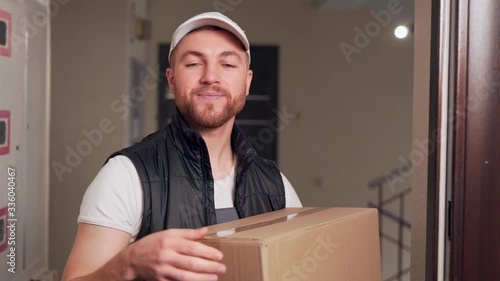 Smiling delivery worker hands over signboard and cardboard box photo